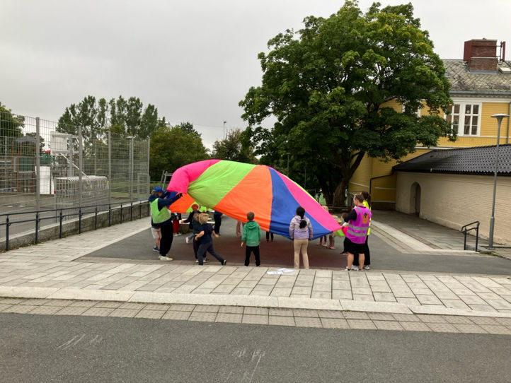 En gruppe mennesker som går med en regnbuefarget paraply