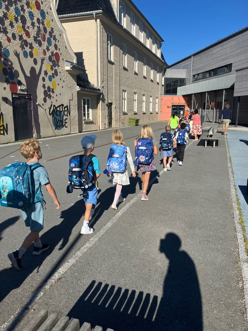 En gruppe mennesker som går bortover skolegården